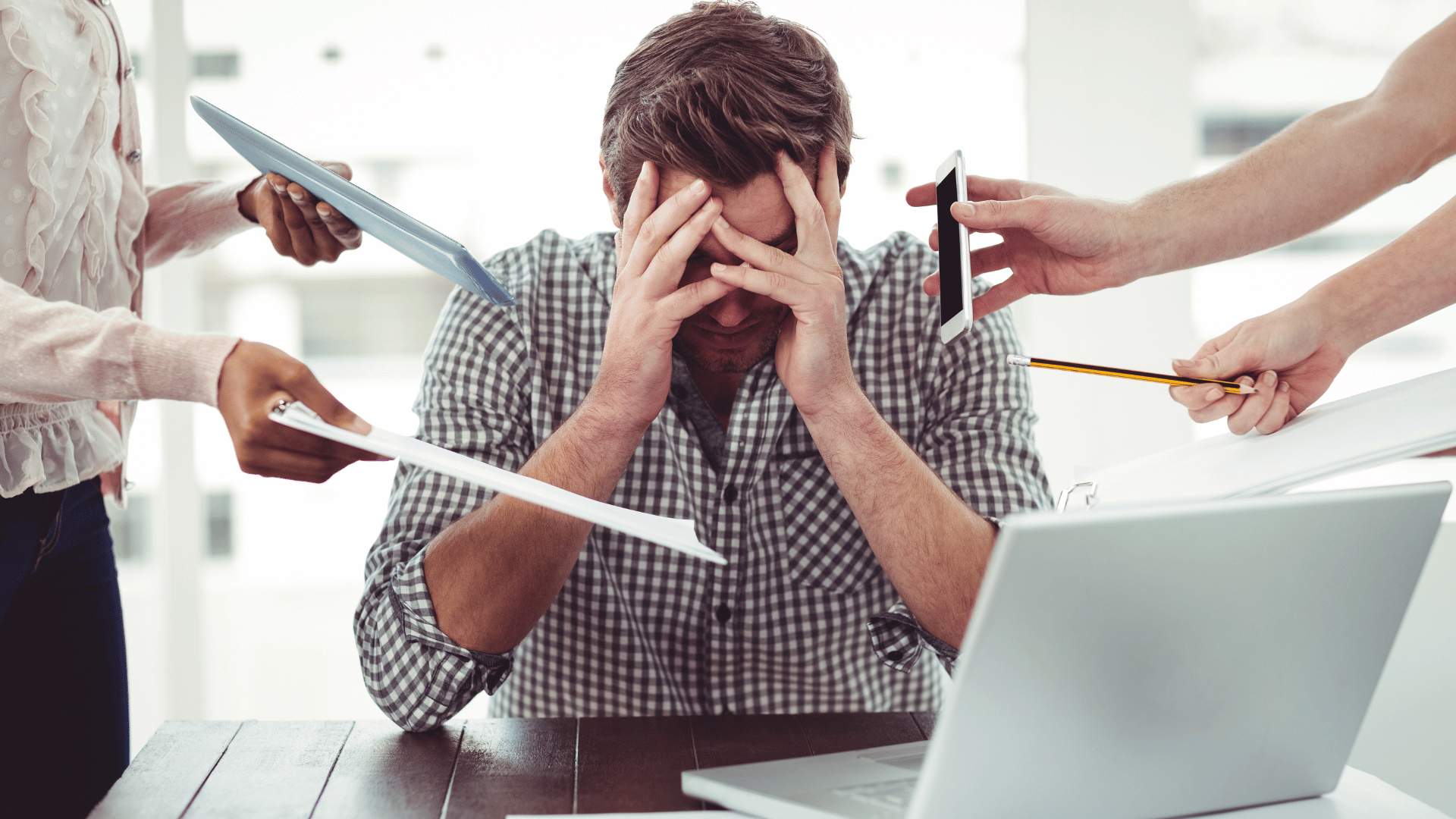 An image of a person working at the office seems very stressed because of the lack of communcation and been expected to do more than he can. Its for an article titled the Real Reason People Quit Small Businesses